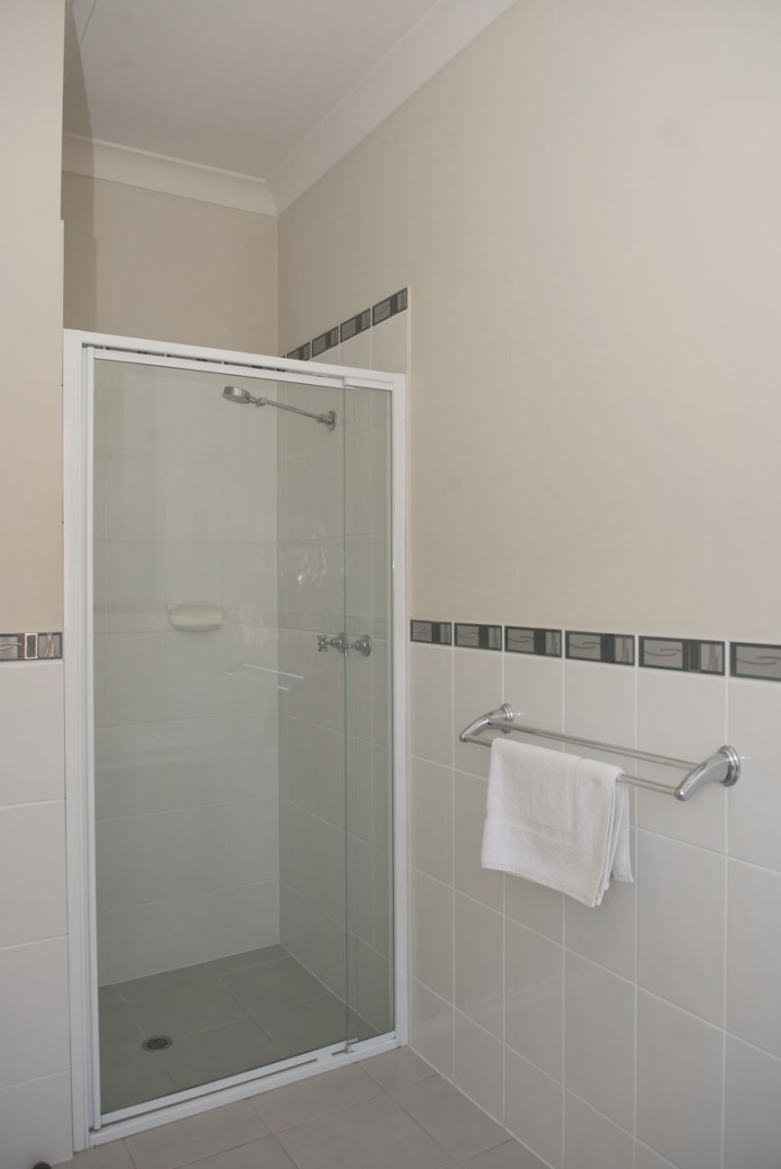 A glass-enclosed shower with a towel rack and a soap dish.