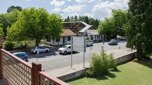 A street view with cars, a pedestrian crossing, and a building with a sloped roof.