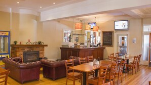 A restaurant with a bar area, leather seating, and a fireplace.