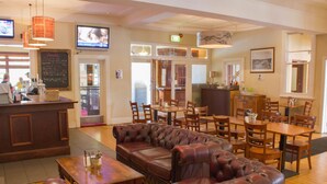 A restaurant with a bar area, leather seating, and multiple dining tables.