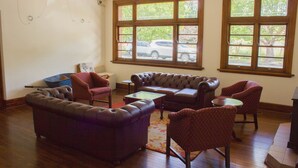 A living room with a sectional sofa, armchairs, and a coffee table. There are large windows with a view of the outside.