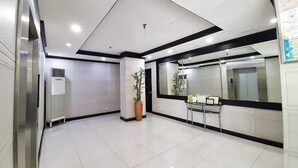 Um hall de entrada limpo e moderno, com piso de azulejos, balcão de recepção e uma grande janela.