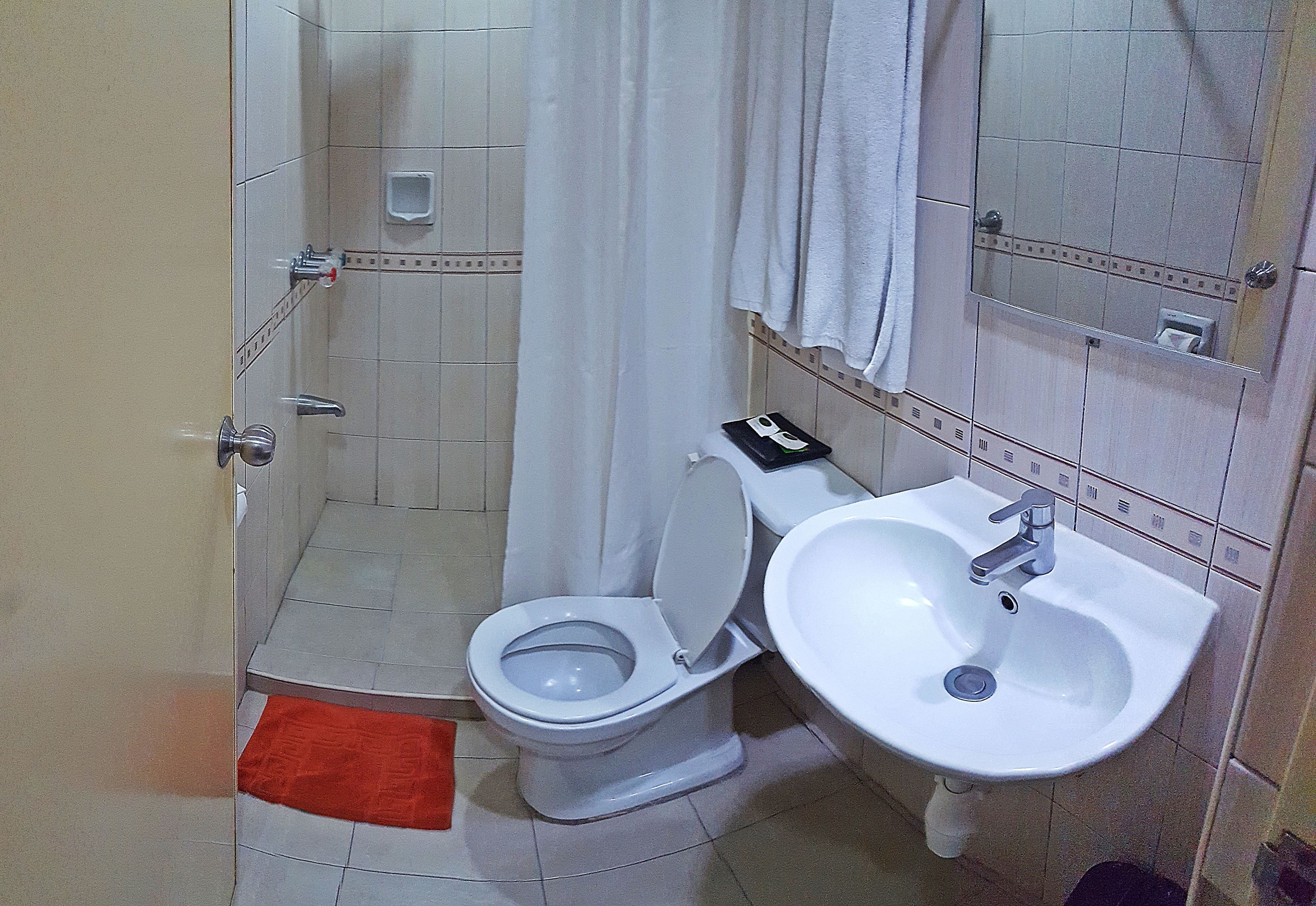 Une salle de bain comprenant des toilettes, un lavabo et un espace douche.