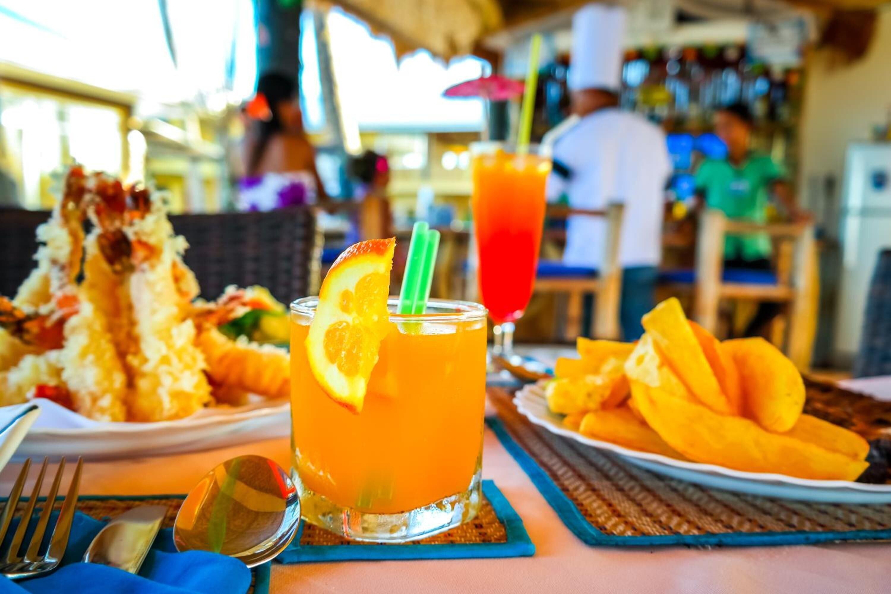 A dining table with a meal, a drink, and a plate of mango slices.