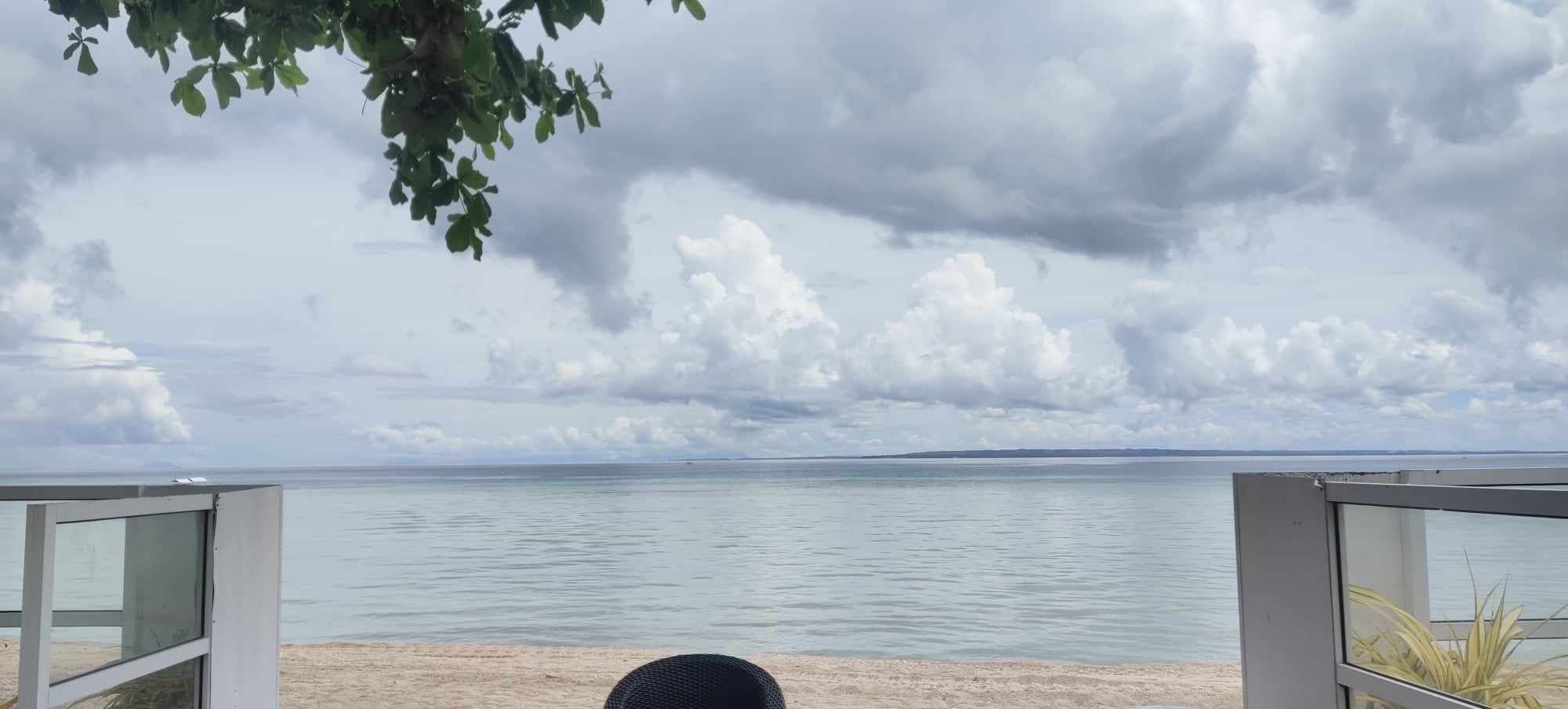 Vista desde un balcón sobre un mar tranquilo con cielo nublado.
