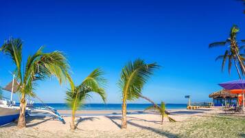 On the beach, white sand, sun loungers, beach umbrellas
