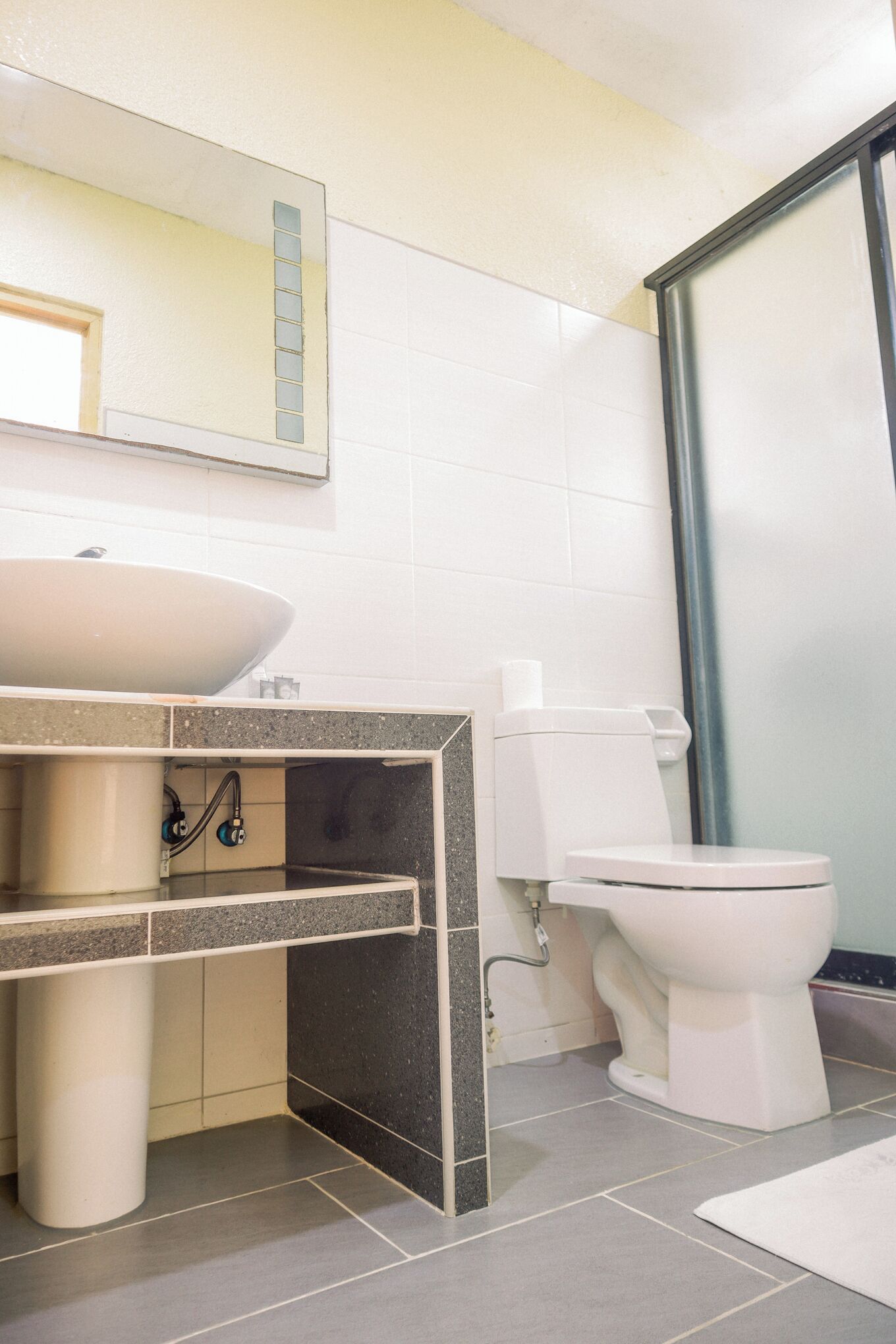 A modern bathroom with a sink, mirror, toilet, and shower area.