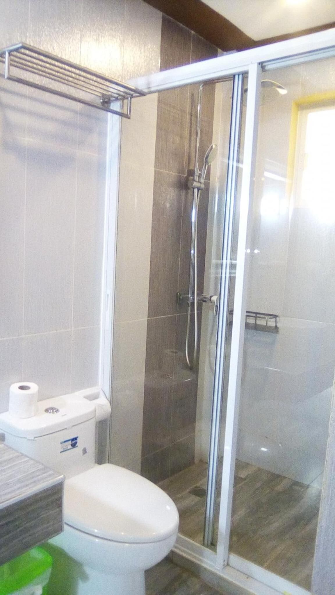 Un baño con inodoro, cabina de ducha y puerta de cristal.