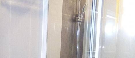 Un baño con inodoro, cabina de ducha y puerta de cristal.