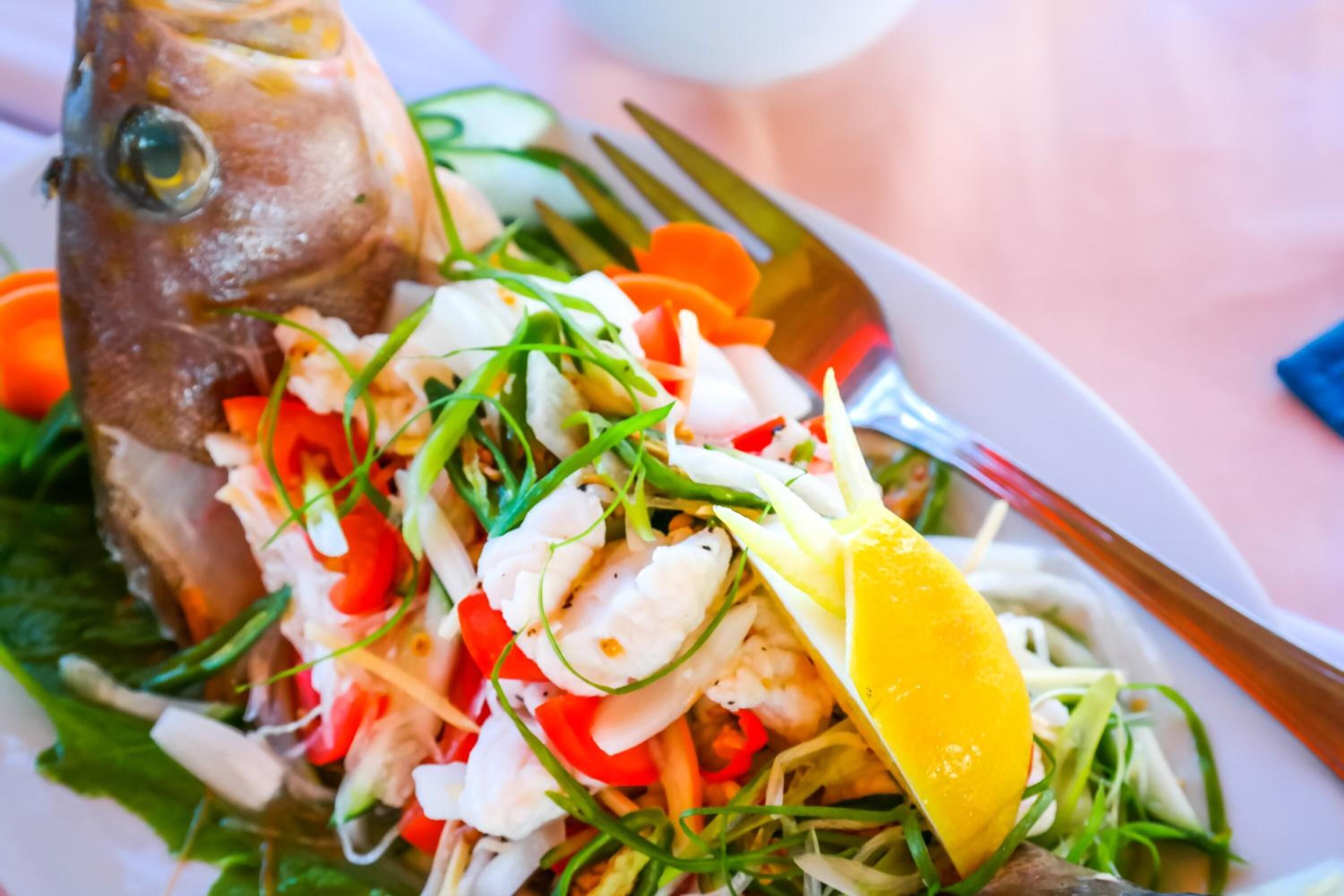 Un plato con cabeza de pescado, camarones y verduras.