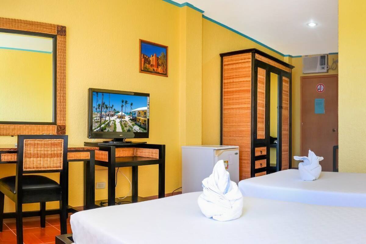 A hotel room with a bed, a desk, a chair, a television, and a door.