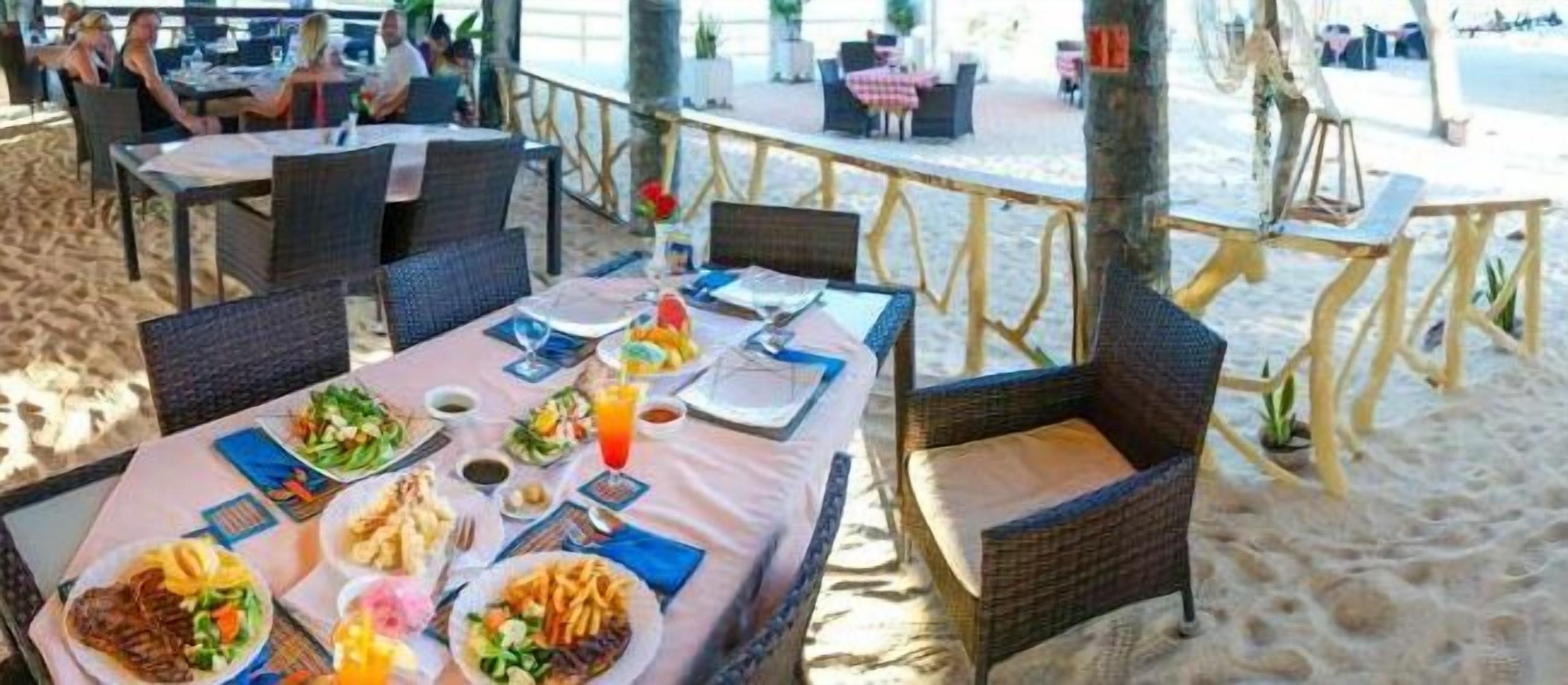 Ein Restaurant direkt am Strand mit Außenbereich, Tischen und Stühlen.