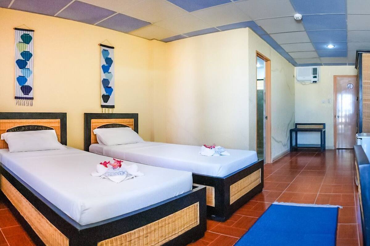 A hotel room with two beds, a desk, a mirror, and a small bathroom.