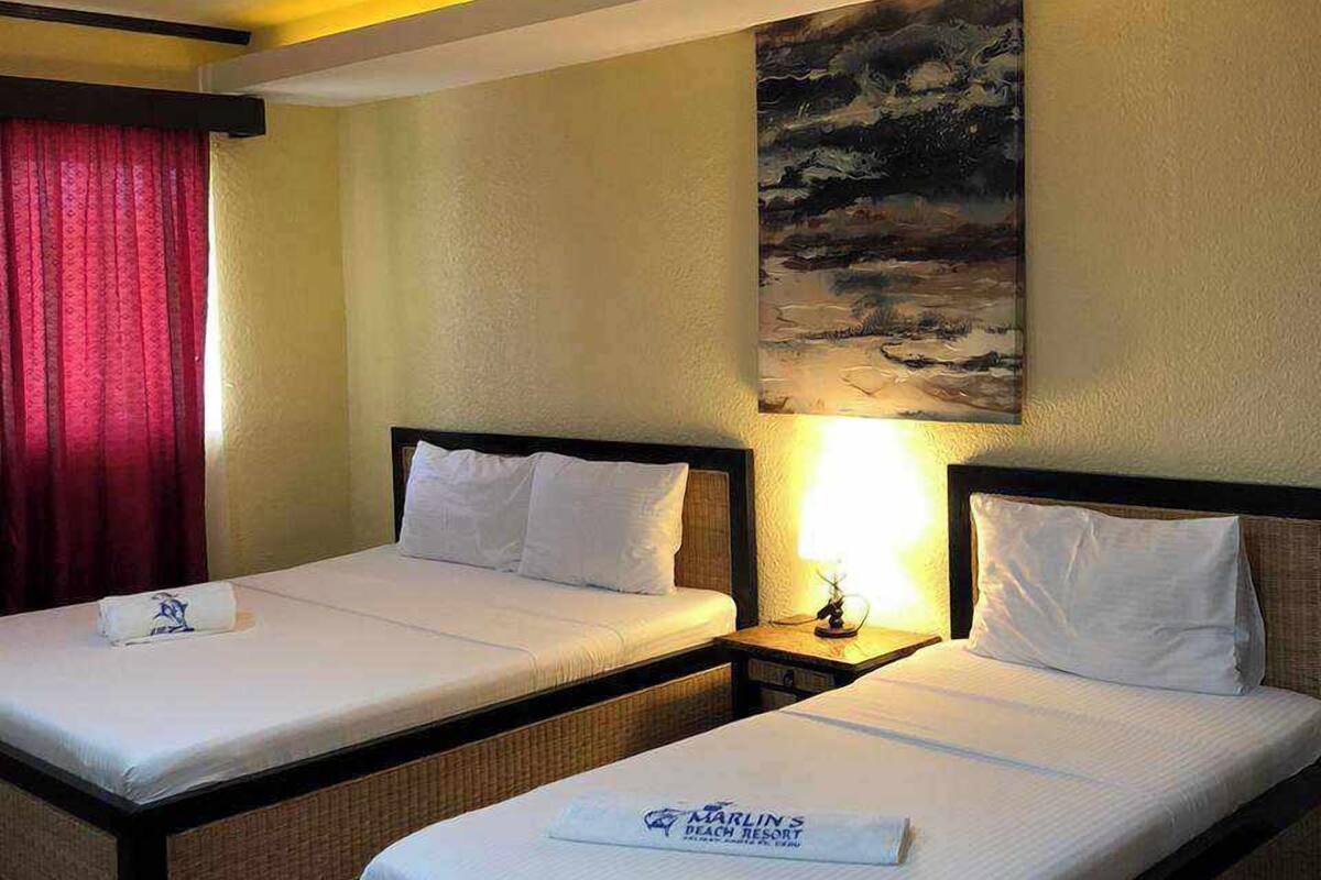 A hotel room with two single beds, a painting on the wall, and a red curtain.