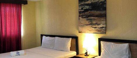 A hotel room with two single beds, a painting on the wall, and a red curtain.