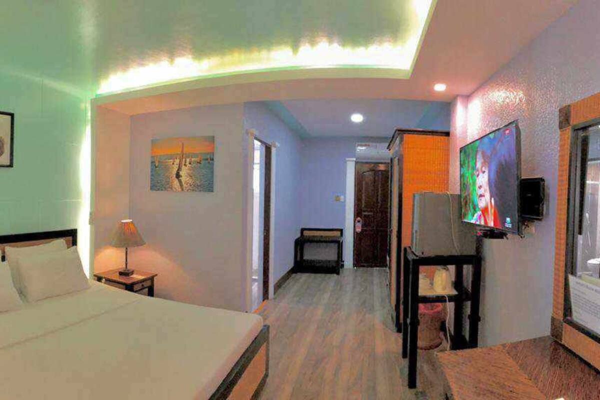 A hotel room with a bed, bedside tables, a TV, and a mirror.