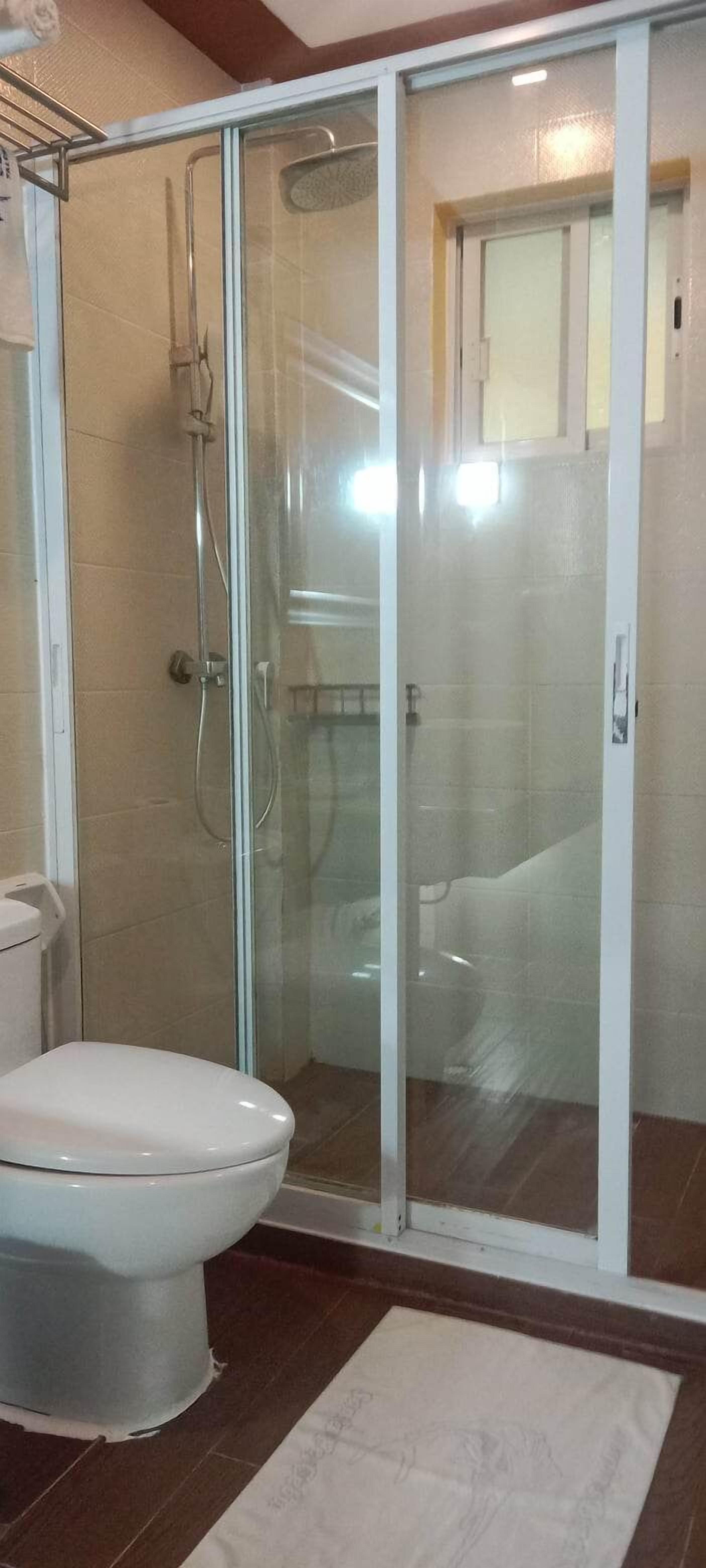 Une salle de bain avec une douche à parois de verre, des toilettes et un lavabo blanc.