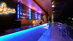 Un espace bar avec un panneau néon, un barman et des tabourets de bar.