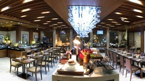 Un restaurant avec des poutres en bois au plafond, un lustre et des tables dressées pour le dîner.
