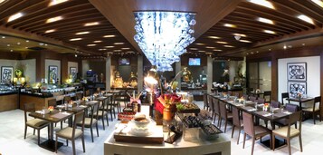 A restaurant with wooden ceiling beams, a chandelier, and tables set for dining.