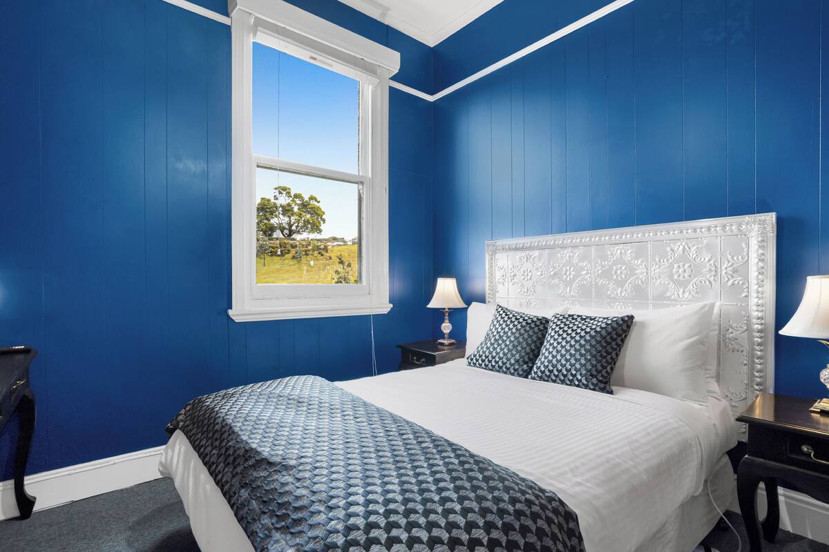 Ein Schlafzimmer mit einem großen Bett, einem weißen Kopfteil und blauen Wänden.