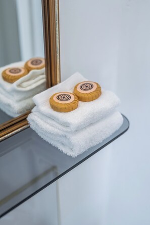 A stack of white towels with wooden bath salts on a glass shelf. - Bischoff Hotel (Waratah)
