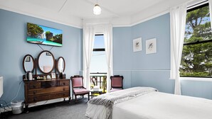 A bedroom with a bed, dresser, chairs, a TV, and artwork on the wall. - Bischoff Hotel (Waratah)