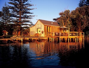 A wooden cabin with a dock extending into a calm body of water, surrounded by trees. - Boathouse - Birks River Retreat - Birks Harbour (Goolwa North)