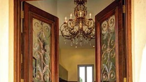 A wooden double door with intricate designs and a chandelier above. - Casa Valeri (Warburton)