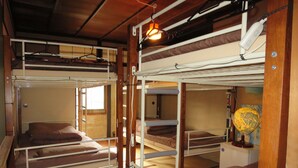 A dormitory-style room with bunk beds, a hanging light fixture, and a globe on a shelf. - Fuji Hostel (Onomichi)