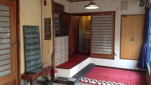 A traditional Japanese room with tatami flooring, a red carpet, and a wooden wardrobe. - Fuji Hostel (Onomichi)
