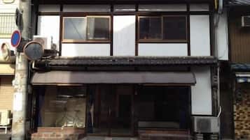 A traditional Japanese building with a tiled roof, a wooden facade, and a storefront with a bicycle outside.