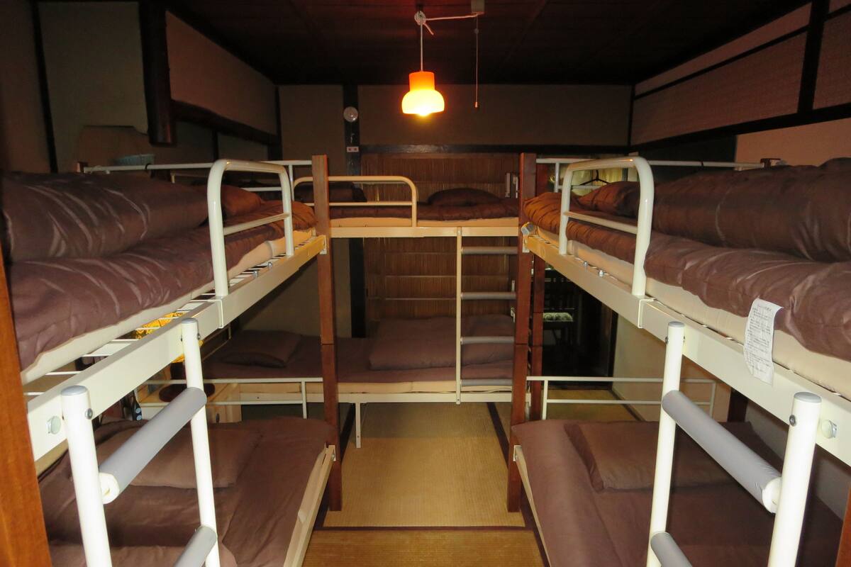 Quarto com beliches de madeira e roupa de cama marrom.