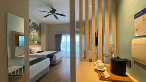 A hotel room with a bed, a ceiling fan, a TV, a plant, and a breakfast setup with a coffee pot and a bottle. - Solea Seaview Resort (Cordova)