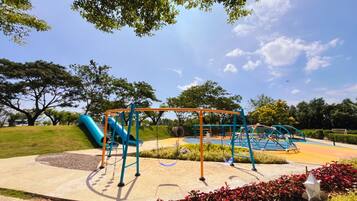 Un parque infantil con tobogán, columpios y estructuras para escalar.