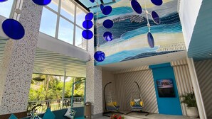 A modern interior with a blue and white color scheme, a hanging light fixture, a sofa, and a small table with red flowers. - Solea Seaview Resort (Cordova)