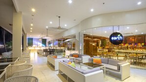 A modern hotel lobby with wicker furniture, a bar area, and a visible restaurant named 'earth'. - Solea Seaview Resort (Cordova)