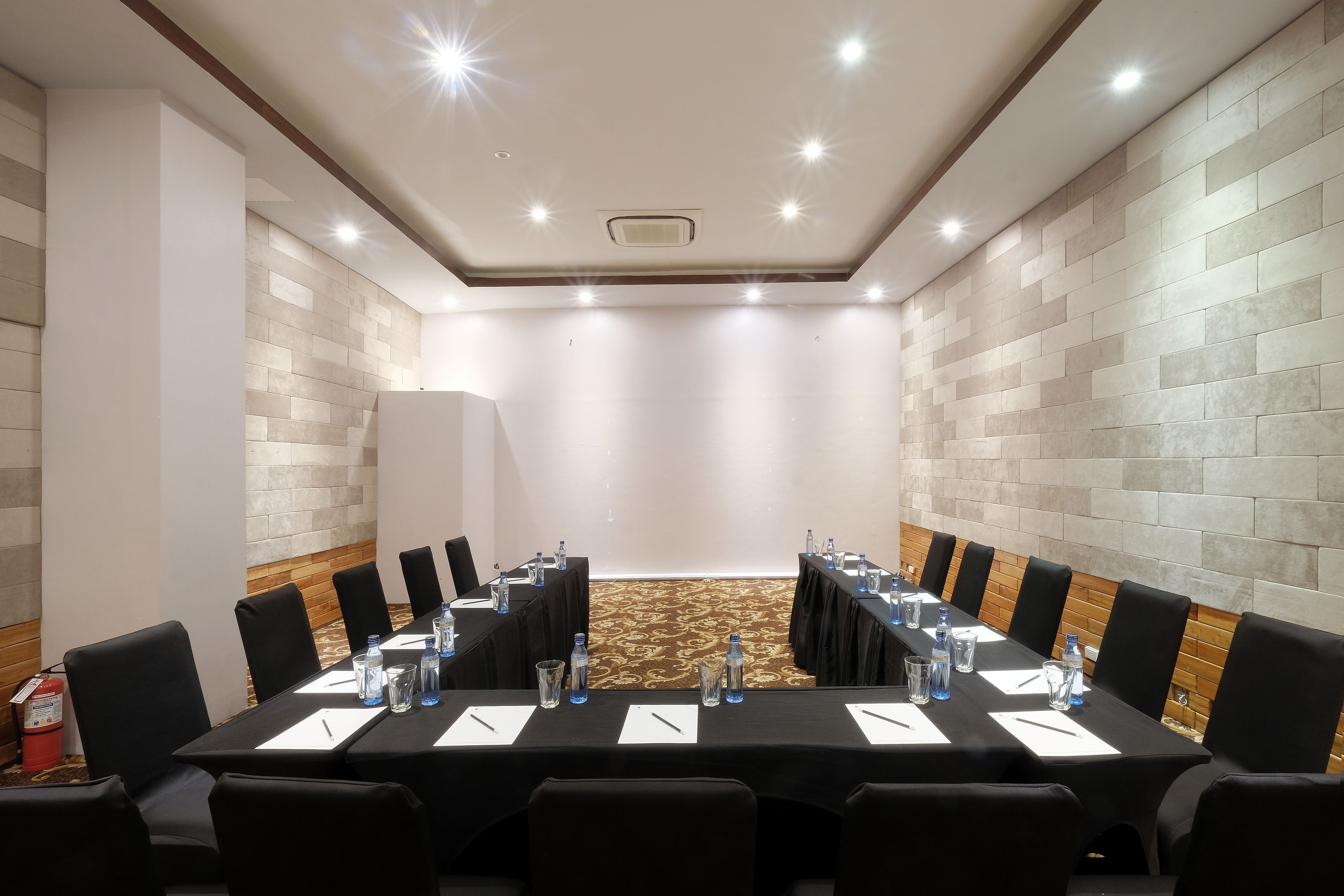A conference room with a long table, black chairs, water bottles, and white notepads.