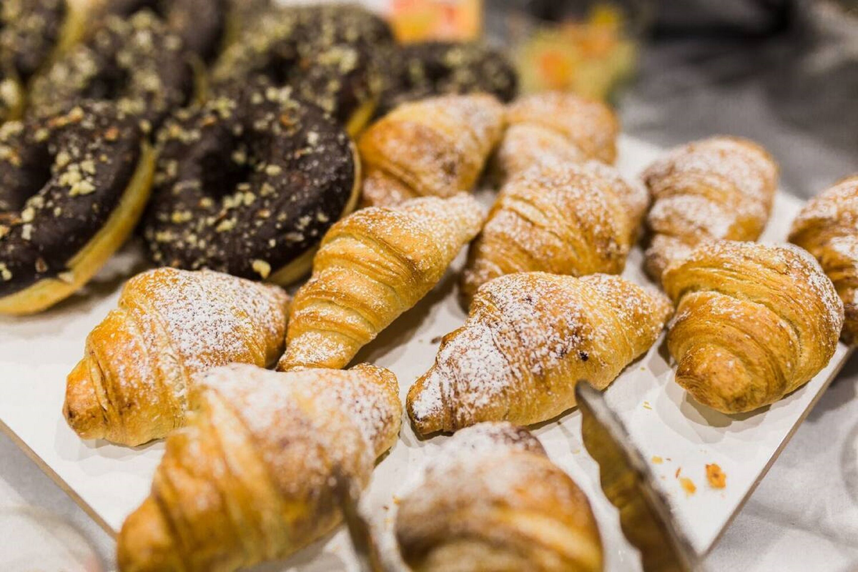 A variety of pastries, including croissants and chocolate-covered items, displayed on a tray.