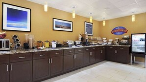 A breakfast area with a counter, microwave, and various food items.