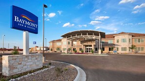 A Baymont Inn & Suites with a modern architectural design, featuring a curved entrance and a landscaped driveway.