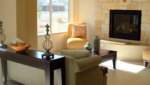 A living room with a stone fireplace, a sofa, a coffee table, and a dining area with a table and chairs.