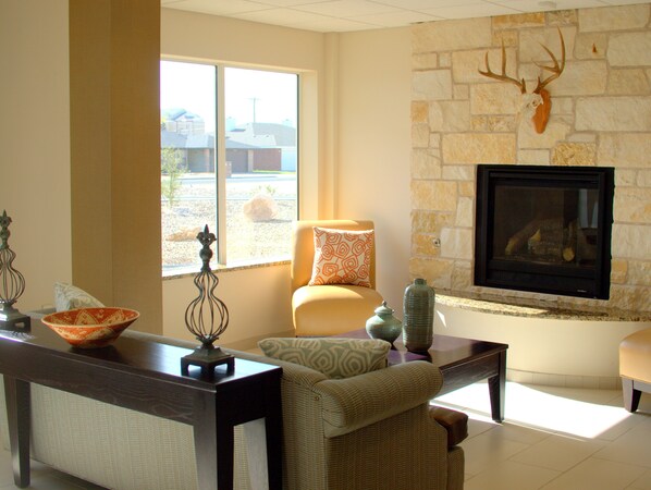 A living room with a stone fireplace, a sofa, a coffee table, and a dining area with a table and chairs.