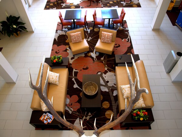 Un vestíbulo con una zona de estar central, sofás y sillones, un tapete estampado y un elemento decorativo.