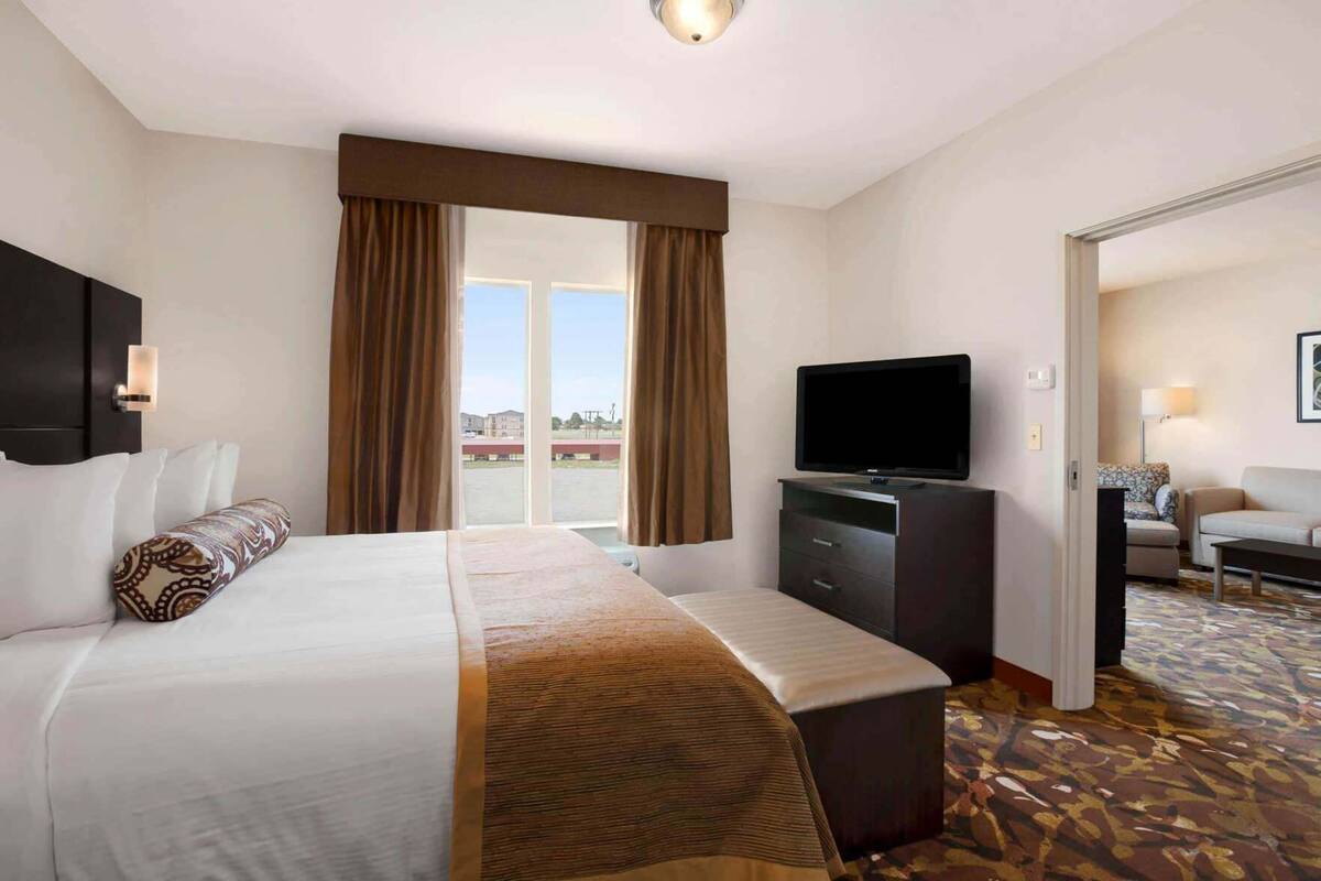 Une chambre d’hôtel équipée d’un lit, d’une télévision, d’une commode et offrant une vue sur l’extérieur.