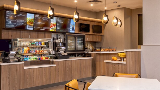 Een modern restaurant met een houten toonbank, een kassa en een menukaart.
