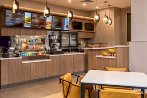 A modern restaurant with a wooden counter, a cash register, and a menu display. - Courtyard New York Manhattan/Times Square West (New York)