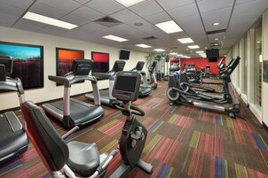 Uma academia com várias esteiras, bicicletas ergométricas e aparelhos de musculação.