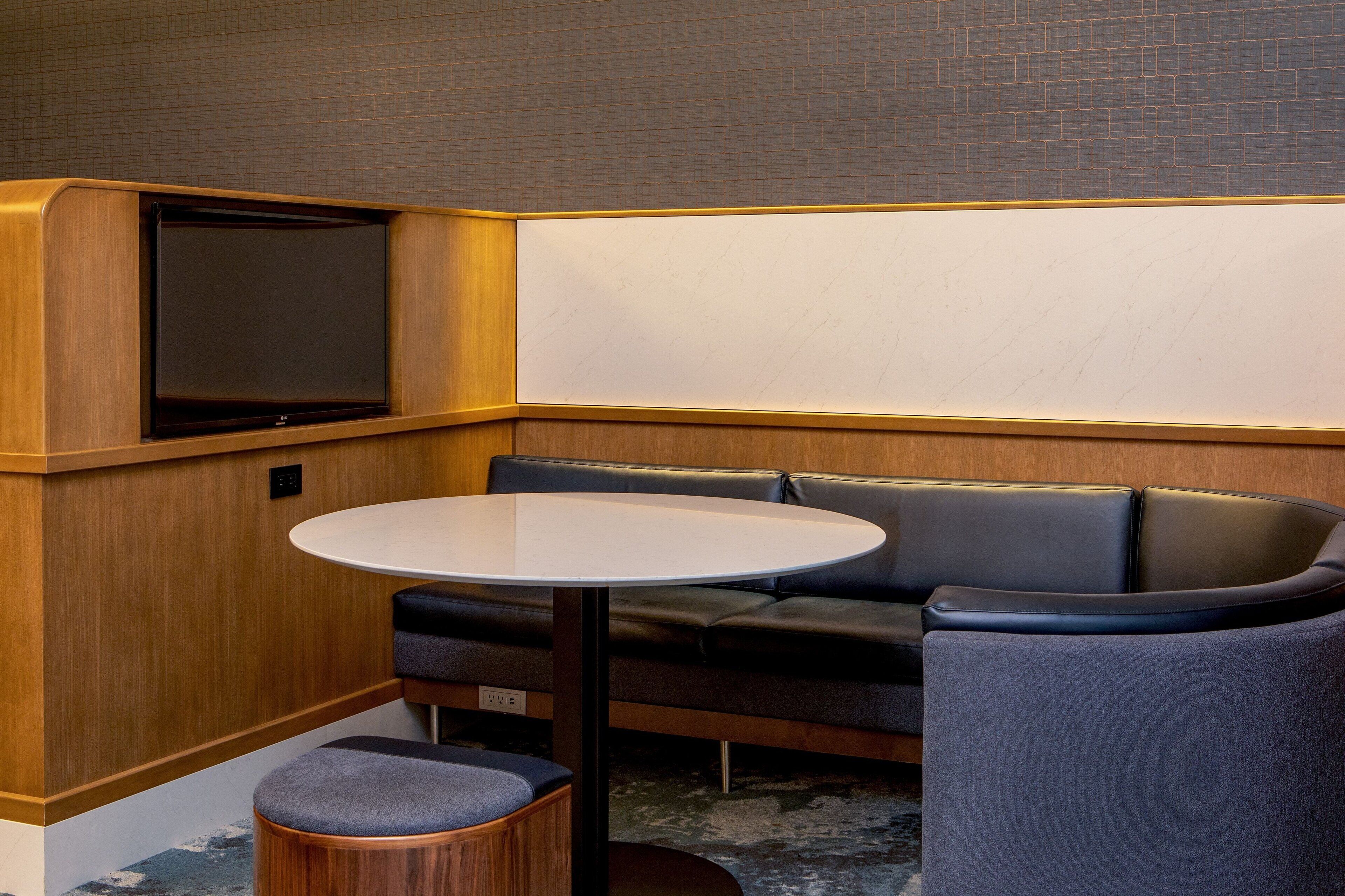 A compact room with a round table, a sofa, and a television.