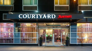Entree van een Courtyard Marriott hotel met glazen deuren, een bord met nummer 307 en een vlag.